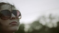Young woman in sunglasses waves hand in the wind and gazes out from backseat of convertible Stock Footage