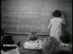 1938: TRAFFIC EDUCATION: Policeman poster. Girl at blackboard writing out Traffic Rule number 6. National Safety Council child safety expert Marian Telford talking (No SOT) w/ two policemen. MS Telford working w/ male educator, teacher or principle. Instructional Video