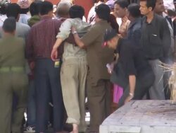 MS ZO Two grieving men's leading away as body of deceased smolders and burning AUDIO / Kathmandu, Central, Nepal Stock Footage