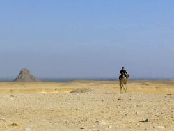 WS Man riding on camel in desert with Black pyramid of Amenemhat III in background / Dahshur, Egypt Stock Footage