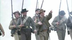 Confederate soldiers march across a field as smoke billows around them. Stock Footage