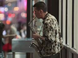 A man on a busy street corner playing the Saxophone at night near Time Square Stock Footage