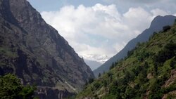 Lush green mountains with puffy clouds and snow capped Himalayan Mountains in background. Stock Footage