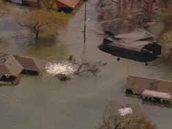 Aerial Chinook helicopter carrying sand bags to broken levee on London Ave. Canal /New Orleans, low angle Stock Footage