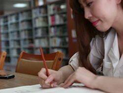 Chinese female student writing on notebook in library,real time. Stock Footage