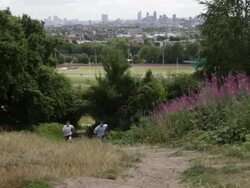 Two male running up hill in park London with skyline in background Stock Footage