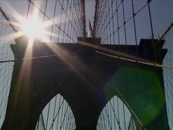 Exterior day shot, pan from the sunny sky above to the center of the bridge. Travel destination -Brooklyn Bridge over the East River Stock Footage