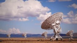 Very Large Array telescopes swivel in unison beneath billowing clouds. Stock Footage