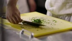 Restaurant cook concentrates on cutting parsley in busy kitchen Stock Footage
