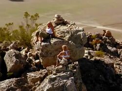 Aerial past 2 women sitting on a mountain top Stock Footage