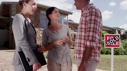 Realtor and couple with keys in front of house with Sold sign Stock Footage