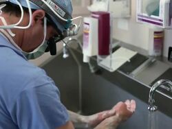 Doctors preparing room for surgery while doctor washes his hands outside Stock Footage