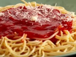 MS DS Parmesan cheese being sprinkled over rotating spaghetti dish topped with tomato sauce for pasta marinara / Los Angeles, California, United States Stock Footage