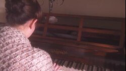 A woman wearing a shawl plays a piano. Stock Footage