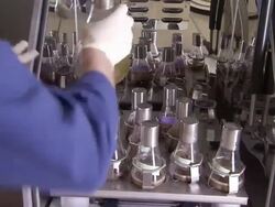 Medium static , A chemist places a flask of liquid with other flasks in a shaking machine. / California Stock Footage