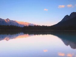 Mountains at sunset reflecting their glow in Alpine Lake Stock Footage