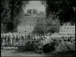 1951: CENTRAL MOROCCO: Berber people (Imazighen, Amazigh) gathered outside in circle, men moving up/down clapping hands, chanting SOT, one male w/ hand drum, women in bangled headresses, veils, moving up/down. camera shake at end. Instructional Video