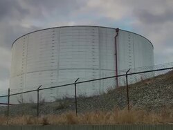 Old gray petroleum storage tank with barbed wire fence - pan Stock Footage