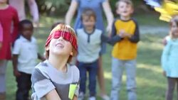 Boy hitting pinata, children watching in background Stock Footage