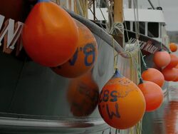 Several red buoys hanging from sides of two fishing boats Stock Footage