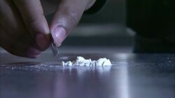 A drug user piles powdered cocaine into a line with a razor blade. Stock Footage