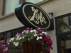 MS woman waters plants outside of Lola's in Cleveland Stock Footage