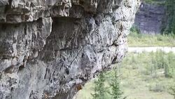 Climber belays teammate on steep cliff above valley Stock Footage