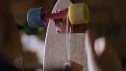 Young business owner hangs price tag around colorful skateboard wheel Stock Footage