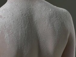 CU SLO MO Shot of nude female Caucasian standing with back to camera, covered in powder on her, she turns / Studio, New York, United States Stock Footage