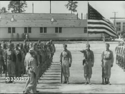 1942: FORT JACKSON REVIEW: HA WS British Prime Minister Winston Churchill walking w/ unidentified officer past soldiers standing at attention w/ barracks BG, Churchill removing hat &amp; officer saluting American flag. WWII, Allied, training, airborne. Instructional Video