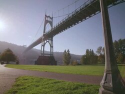 WS View of St. Johns Bridge large steel suspension bridge in Gothic style, looms large over Willamette River and park beneath it / Portland, Oregon, United States Stock Footage