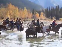 Cowboys and Cowgirls crossing river on horseback Stock Footage