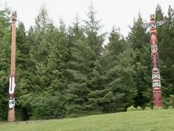 "Two thin totem poles, brightly painted, evergreen trees behind, near Ketchikan, Ketchikan Borough, Alaska." Stock Footage