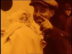 Families holding U.S. flags stand on the deck of a boat as they approach Ellis Island. News Clip
