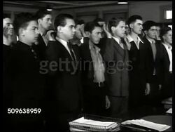 1941: SIGNING UP: Headline 'War With Japan' US Recruits in civilian clothing walking in line, being sworn in, walking into HQ Recruit Depot, being issued uniforms, half-dressed soldiers measured for boots, holding duffle bags & issued rifles. WWII. Instructional Video
