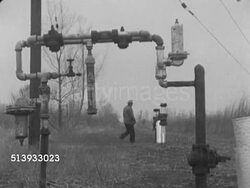 1952: GULF COAST PIPELINE: LA WS Curved piping standing in rural landscape w/ wooden telephone pole & regulating equipment BG, male in coat & hat walking up to white curved piping adjusting something.   Safety, flow, pressure, control, monitoring. Instructional Video
