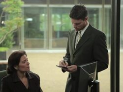MS TD Businesswoman at desk with younger male executive standing, discussing / Portland, Oregon, USA Stock Footage