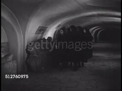 1940: VATICAN CITY: SAINT PETER'S BASILICA: GROTTOES: Women in black, possibly nuns, walking down crypt hallway, passing two sarcophagus in hall, tombs in small alcove, tomb of Pope Marcellus II (1501-1555), Innocent I tomb. Instructional Video