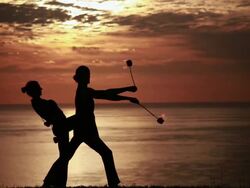 MS Sihouetted couple perform poi dance together with fireballs in front of fiery sunrise and ocean / Montezuma, Costa Rica Stock Footage