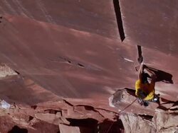 MS ZO Looking down onto climber heading up crack and Camera bit shaky in  Person holding rope in seen on ground / Indian Creek, UT, USA Stock Footage