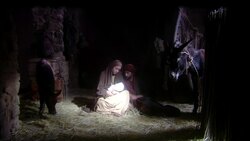 Virgin Mary sitting holding baby Jesus sitting on straw floor on manger with Joseph with Calf and Donkey Stock Footage