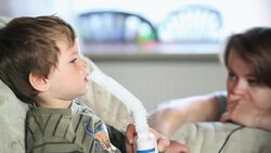 A mother comforts her little boy as he breathes near a nebulizer to inhale medicine. Stock Footage