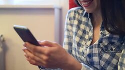 smiley woman sitting on red chair and using her smartphone at home Stock Footage