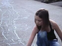 MS Girl looking at camera and smiling while drawing the world's longest hopscotch court aling the sidewalk / Langley, British Columbia, Canada.    Stock Footage