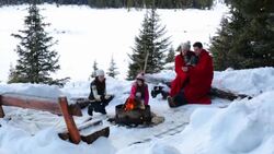 Family toasting marshmallows at fire pit in snow Stock Footage