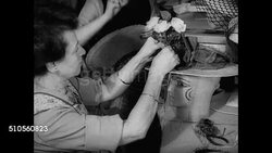 1947: FASHION HAT ACCESSORIES: MS Woman entering 'John Frederics' store. INT MS Woman adding flowers to hat design. MS Designing net on sun hat. VS Frederics (unconfirmed) designing hat w/ necktie female designers BG. MS Working on wide brim hat. NYC Instructional Video
