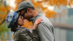 New York couple in love nuzzle and exchange kisses in autumn park (dolly-shot) Stock Footage