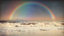 A full rainbow is reflected on the  ocean horizon as a cruise ship passes by. Stock Footage