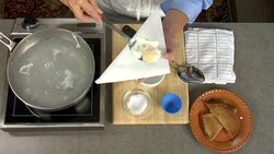 Overhead removing the cooked poached egg from a pan of hot water and placing on toast. Stock Footage