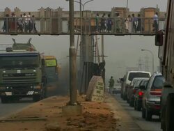 MS View of cross bridge and pedestrian crossing street with smoke coming into muffler / Lagos, Nigeria Stock Footage
